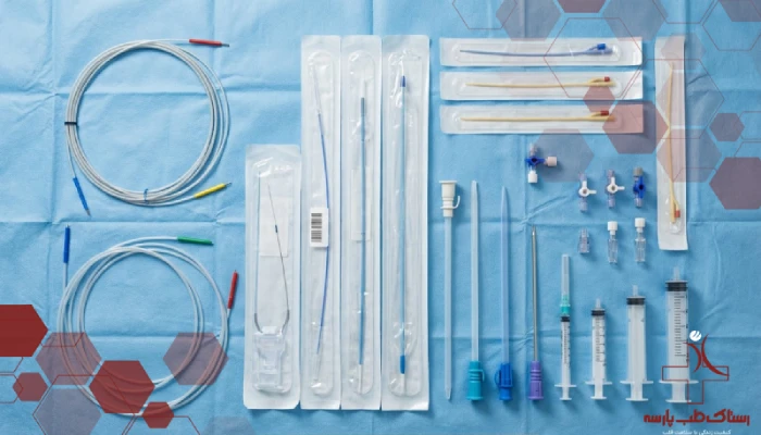 تصویر مجموعه کامل ملزومات مصرفی آنژیوگرافی شامل وایر، کاتتر، شیت و سرنگ روی کاور استریل.